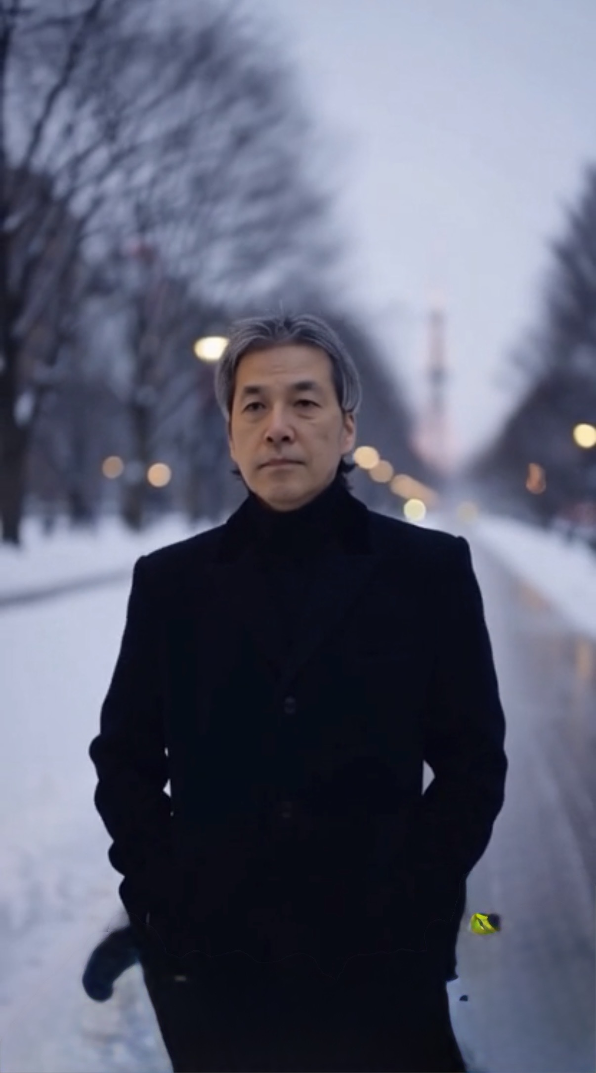 January M Itzki en manteau noir dans une avenue enneigée de Sapporo